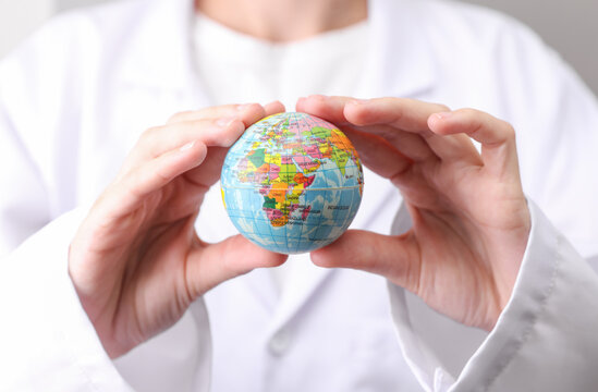 Doctor in white medical gown holding globe model