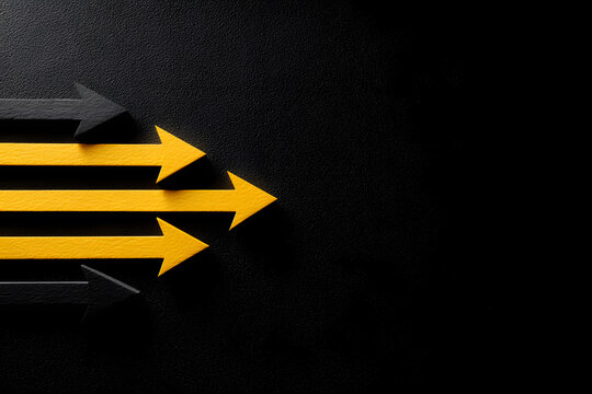 Leadership concept, yellow leader arrow leading black arrows, on black background with empty copy space on left side.