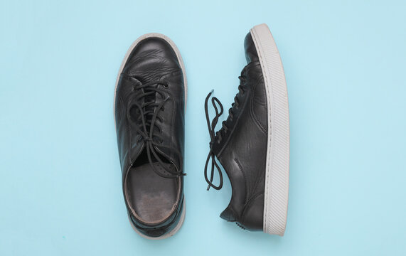 Black leather classic men's sneakers with light sole, blue background. Top view