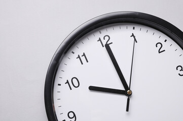 Fototapeta premium Round wall clock with black hands on a gray background. Time concept.