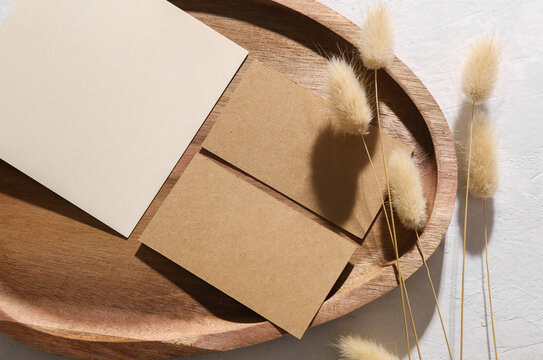 White blank invitation card and business cards mockup in wooden tray with dry grass on concrete background
