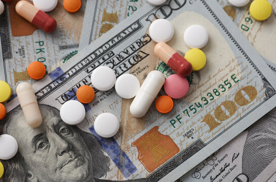 Many different pills on hundred dollar bills. Medicine financing concept
