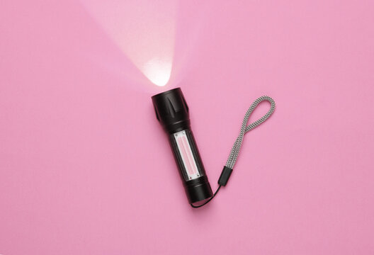 Pocket flashlight on pink background.