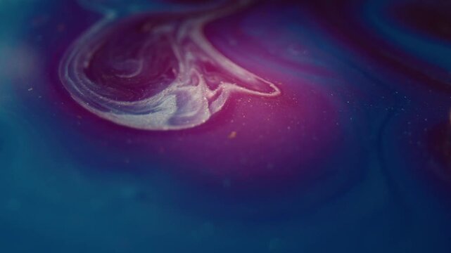 Top-down macro shot of alcohol ink colors blending in a cinematic swirl of pink and blue, representing an emotional evolution over time in a studio packshot.