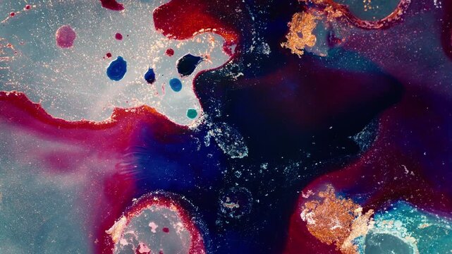 perspective of blue and red alcohol ink swirling with gold metallic accents. Vibrant and ethereal composition capturing fluid evolution during a creative studio session.