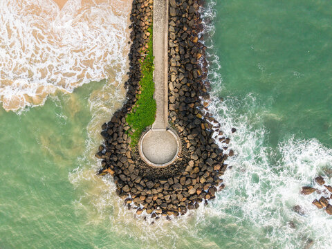 Aerial view of the circular stone pier at View Point - Mahamodara fishing spot with turquoise waves crashing against the rocks and sandy beach in Galle, Sri Lanka.