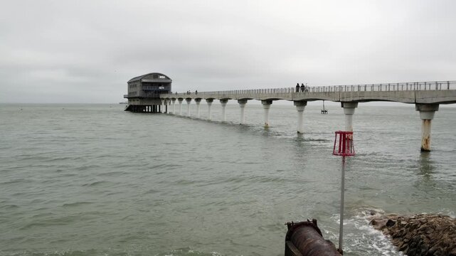 Handheld shot of RNLI Bembridge lifeboat station pier and sea on cloudy day