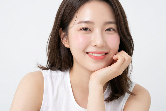 흰색 배경에서 손으로 턱을 괴고 환하게 웃고 있는 20대 피부 미인 아시아 여성 뷰티 클로즈업