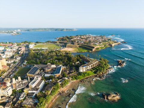 Aerial view of Galle Fort with its historic stone walls, terracotta rooftops, and the turquoise Indian Ocean coastline under a clear blue sky Galle, Southern Province, Sri Lanka.
