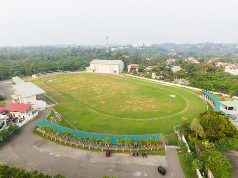 Aerial view of a green sports field with an oval track surrounded by lush tropical trees and urban buildings in Galle, Southern Province, Sri Lanka.