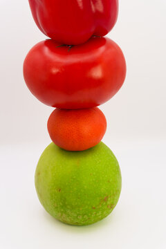 Mandarin, apple, tomato and sweet pepper in the form of a tower on a white background, the concept of healthy eating from fruits and vegetables, health care, fruit diet, vegans and vegetables. High qu