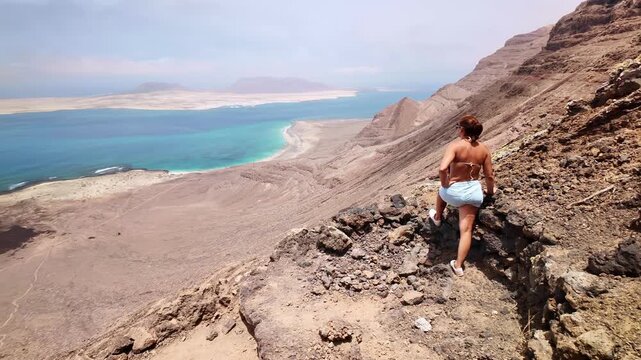 Adventurous woman hiker overlooking Risco beach from a cliff in Lanzarote