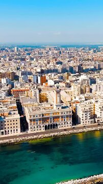Vertical video. Bari, Italy. The Lungomare di Bari seafront promenade, elegant early 20th-century buildings lining the Adriatic coast, Drone footage under clear summer sky. Drone footage. Rich colors