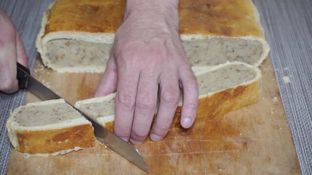 Cutting traditional homemade buckwheat pie close-up, Chef slicing a freshly baked rustic pie stuffed with buckwheat kasha and meat or mushrooms. comfort food concept.
