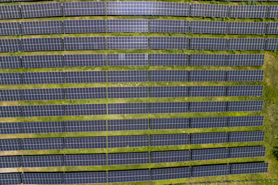 Aerial view of a large solar panel farm with rows of photovoltaic panels installed on green grass in Guanaja, Bay Islands Department, Honduras.