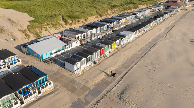 Aerial view of Strand Wijk aan Zee beach huts lined up along the sandy coast and grassy dunes Wijk aan Zee, North Holland, Netherlands.