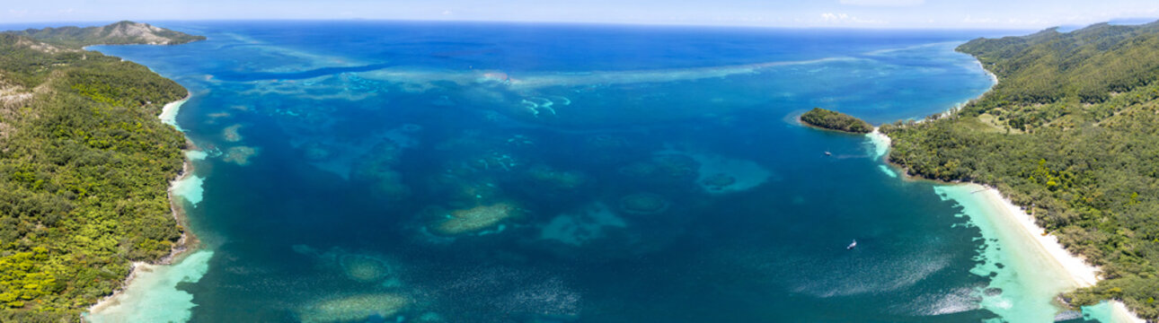 Aerial view of the turquoise waters and lush tropical coastline of Guanaja island featuring coral reefs and white sand beaches in Guanaja, Bay Islands Department, Honduras.