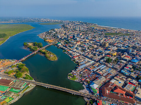 Aerial view of the urban landscape and bridges crossing the Mesurado River with colorful rooftops and the Atlantic Ocean in the distance Monrovia, Montserrado, Liberia.