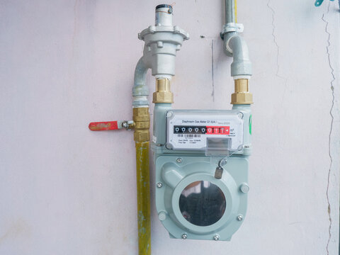 ​Gas meter installation on an outdoor wall, natural gas utility meter with a pressure regulator and a red shut-off valve for residential energy consumption measurement and monitoring