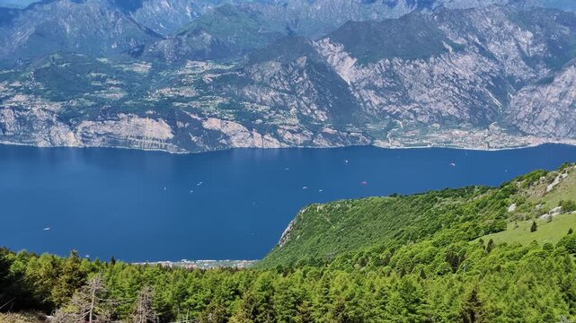 Aerial view of Garda lake from Monte Baldo with lush green forest, blue water, mountain panorama, travel destination, italian landscape