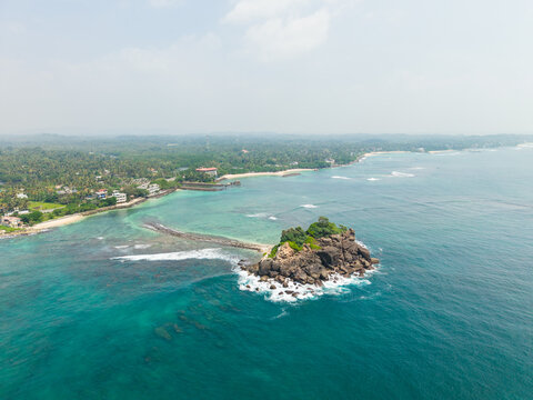 Aerial view of Devil's Rock surrounded by turquoise ocean waters and a lush tropical coastline Ahangama, Southern Province, Sri Lanka.