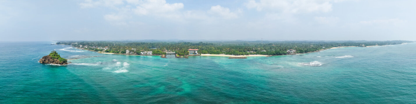 Aerial view of Devil's Rock formation, turquoise ocean waves, and lush tropical coastline with palm trees Sri Lanka.