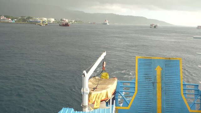 Ferry departing harbor across strait with dramatic storm clouds and mountain coastline