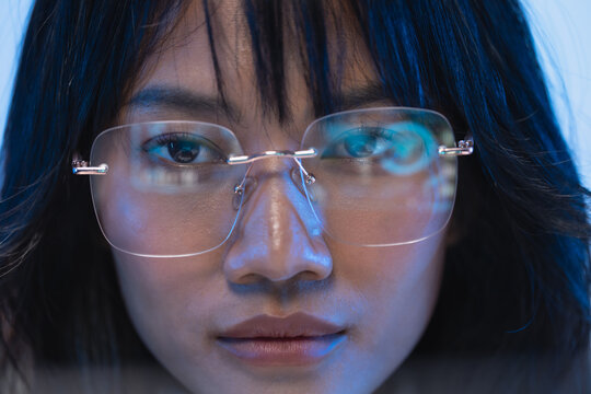 Detailed close up portrait of a beautiful young Asian female programmer wearing modern rimless eyeglasses with subtle code reflection on the clear transparent lenses