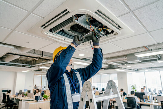 オフィス天井エアコンを点検する作業員