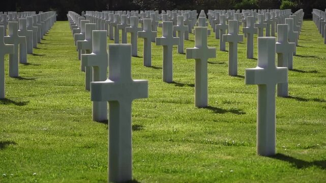 American cemetery in Normandy with rows of military grave markers on green lawn. World War II remembrance and national tribute