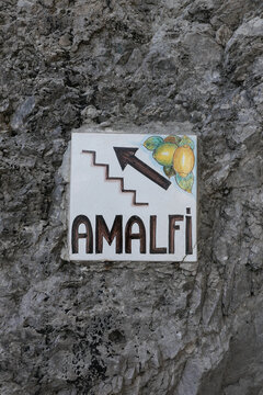 Amalfi ceramic road sign with lemon on stone wall in Italy