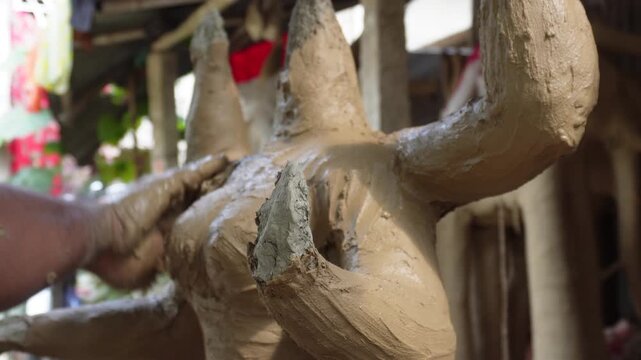 Artisan crafting traditional clay idol in cultural festival workshop