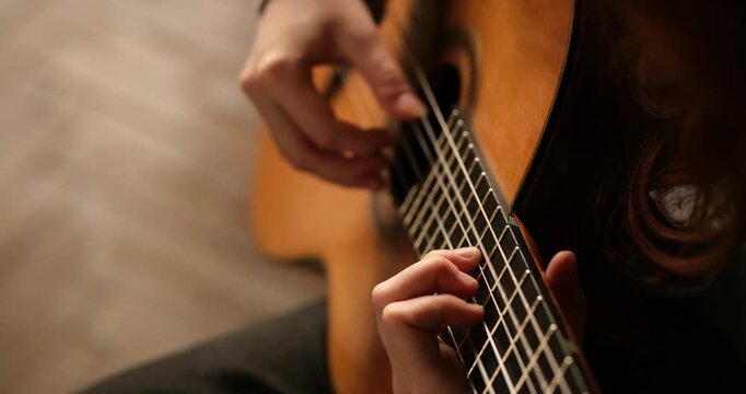 musician's hand delicately plucking the strings of a classical guitar near the sound hole. making it ideal for music, performance, arts, culture