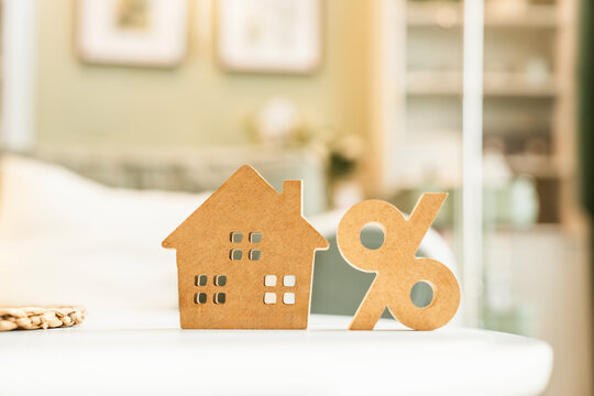 House model with percentage sign on table, property mortgage interest rates and real estate investment loan concept.