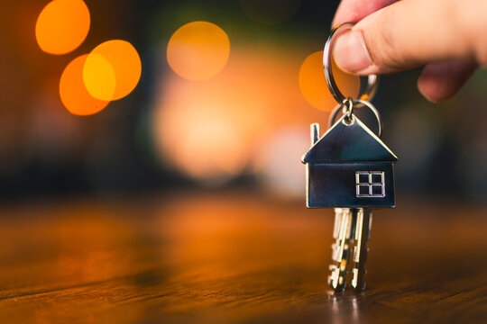 Hand holding house key with bokeh background, real estate investment, home ownership and mortgage concept.