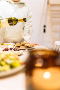 Pouring white wine during cozy dinner inside modern tiny house vertical frame
