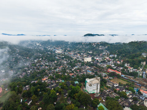 Aerial view of the urban landscape of Kandy nestled among lush green hills with mist rolling over the mountains under an overcast sky Kandy, Central Province, Sri Lanka.