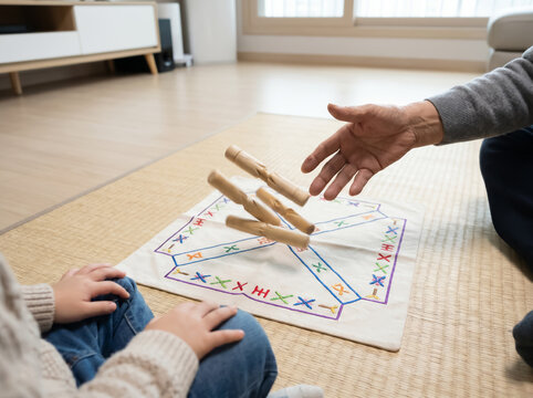 Senior and young child playing a traditional Korean Yut Nori board game with wooden sticks in the air, showing intergenerational bonding and family game time at home.