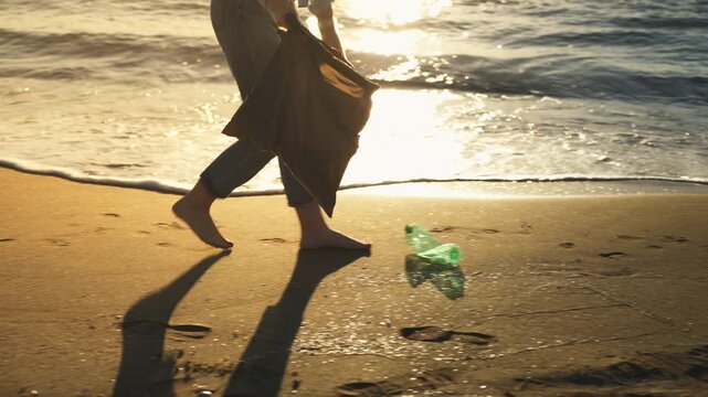 Young woman removing plastic waste from beach with trash bag, symbolizing climate change impact, environmental responsibility, and global sustainability efforts.