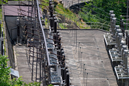 Aerial view of the electrical substation infrastructure with high-voltage insulators and power lines near the Verzasca Dam in Gordola, Ticino, Switzerland.
