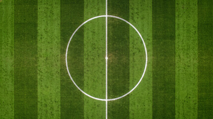 Obraz premium Aerial close up top view of soccer pitch center circle green grass texture at night.