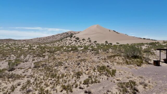 drone shot approaching the "Singing Dune" in te Altyn Emel National Park of Kazachstan. A remote sand dune with oasis in the background