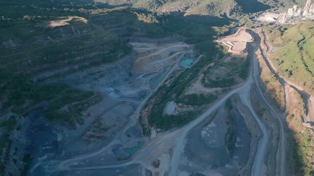 Massive open pit mining complex spreads near Fercal, Bras&iacute;lia, Federal District, Brazil, top down overhead drone yaw reveal terraced excavation systems, haul road networks, engineered extraction scape