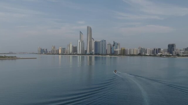 A technical aerial maneuver combining a forward dolly movement, a downward altitude decrease, and an upward camera gimbal pitch. This shot tracks a motorboat with Abu Dhabi skyline as backdrop