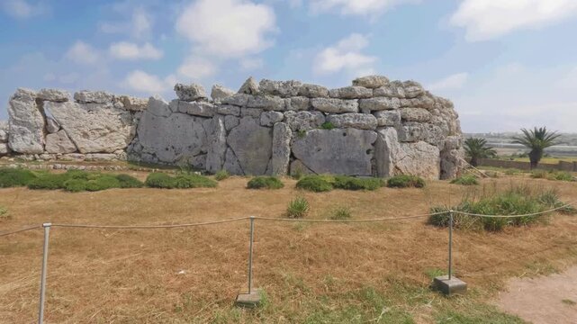 The massive stone walls of Ġgantija Temples in Malta stand prominently under a bright blue sky. Ideal for historical documentaries or cultural tourism projects.