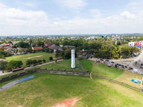 Aerial view of the historic Matara Clock Tower and stone ramparts of the fort surrounded by lush greenery and urban landscape in Matara, Southern Province, Sri Lanka.