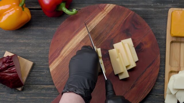 Top view of knife slicing fresh mozzarella cheese on a wooden board. Preparation of ingredients for filo pastry pie. Culinary cooking process in kitchen.