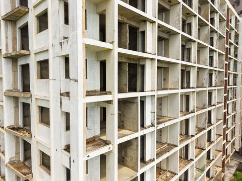Aerial view of the geometric grid pattern of an unfinished concrete apartment building with empty window frames and weathered walls in Galle, Southern Province, Sri Lanka.