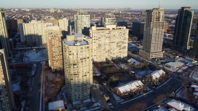 Aerial shot flying in a circular pattern over downtown Mississauga, Ontario, Canada during a cold, sunny winter December day. Looking east, with condominium towers visible and towards Toronto, 2021.