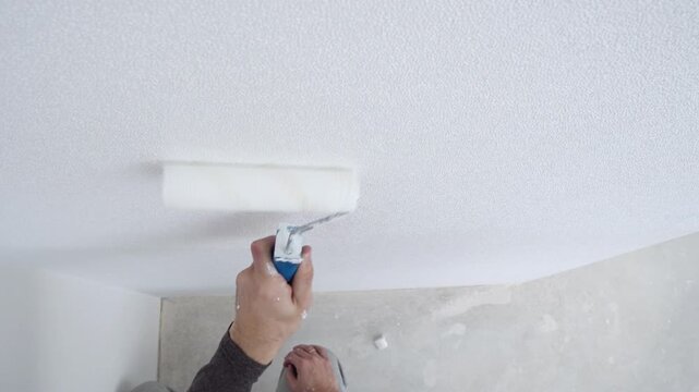 A builder paints a wall with a roller white, construction and renovation